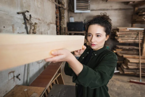 Tischler überprüft verschwommenes Holzbrett in Werkstatt — Stockfoto
