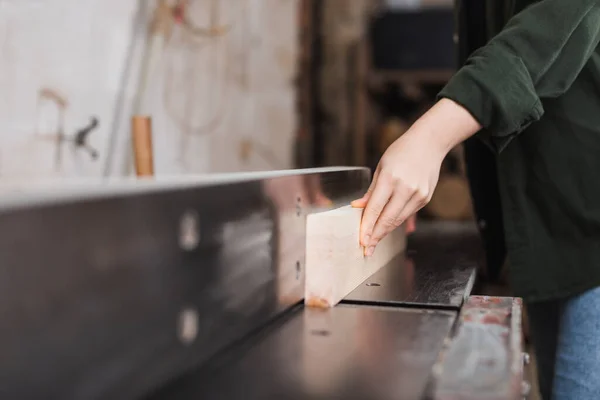 Cropped view of woodworker holding wooden plank near jointer machine — Stock Photo