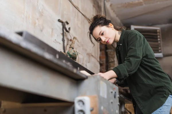 Молодая ремесленница, работающая в мастерской на размытой столярной машине — стоковое фото