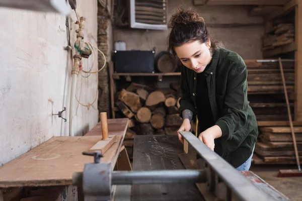 Carpenter using jointer machine while working in workshop — Stock Photo