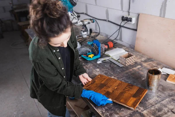 Carpenter applying wood stain on plank in workshop — Stock Photo