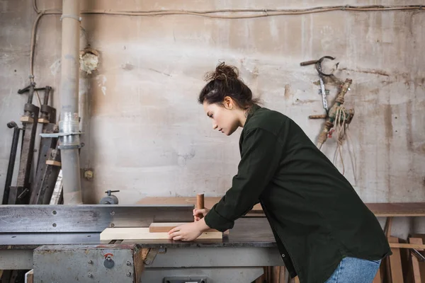 Vue latérale du menuisier utilisant une machine de menuiserie en atelier — Photo de stock