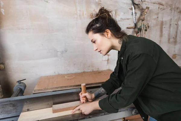 Side view of brunette woodworker using jointer machine — Stock Photo