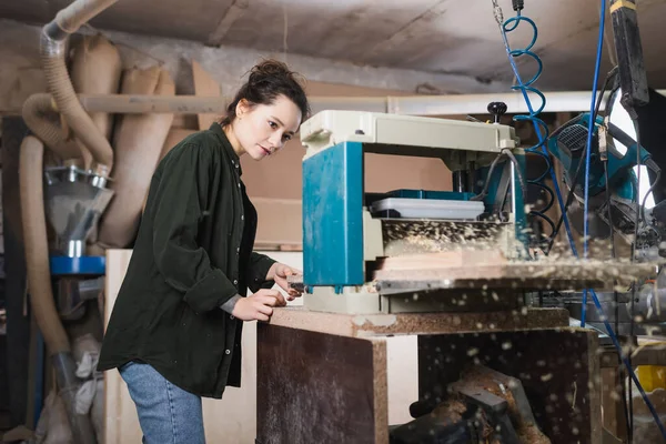 Jeune menuisier travaillant avec raboteuse d'épaisseur en atelier — Photo de stock