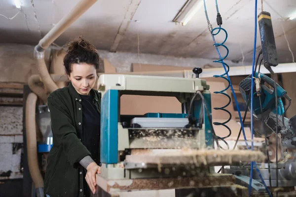 Woodworker using thickness planer while working in workshop — Stock Photo