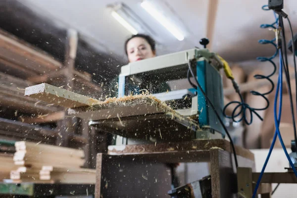 Segatura vicino spessore banco e falegname sfocato in officina — Foto stock