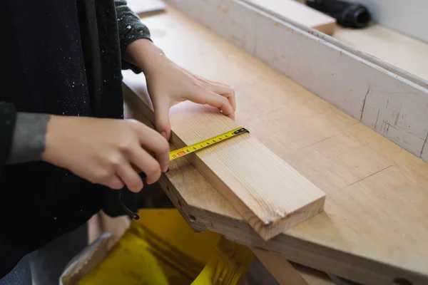 Vista recortada del diseñador de muebles midiendo tablero de madera en taller - foto de stock