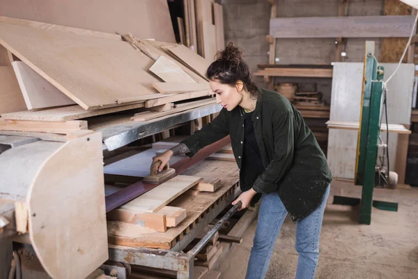 Vue latérale de la planche de bois de polissage de charpentier dans l'atelier — Photo de stock