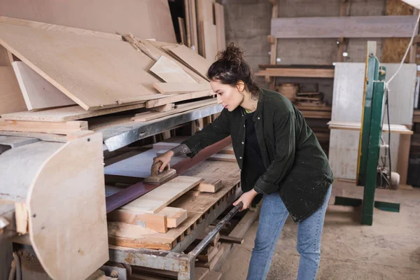 Side view of carpenter polishing wooden plank in workshop — Stock Photo