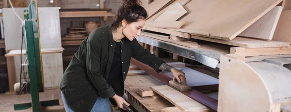 Vista laterale del carpentiere che lucida il bordo di legno nell'officina, bandiera — Foto stock