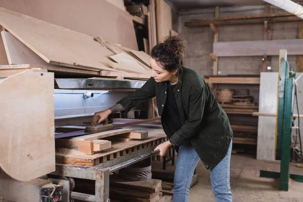 Jeune charpentier polissage planche en bois dans l'atelier — Photo de stock