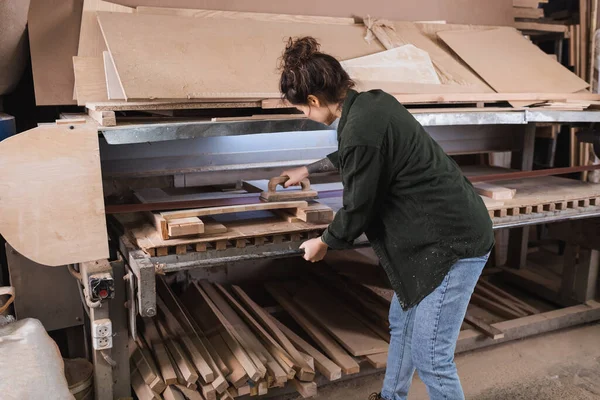 Carpenter polishing plank near boards in workshop — Stock Photo