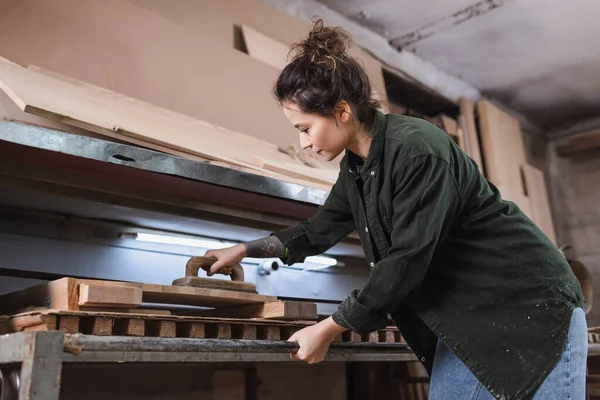 Vue latérale de la brune charpentier polissage planches en bois dans l'atelier — Photo de stock