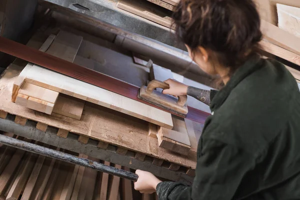 High angle view of tattooed furniture designer polishing wooden plank in workshop — Stock Photo