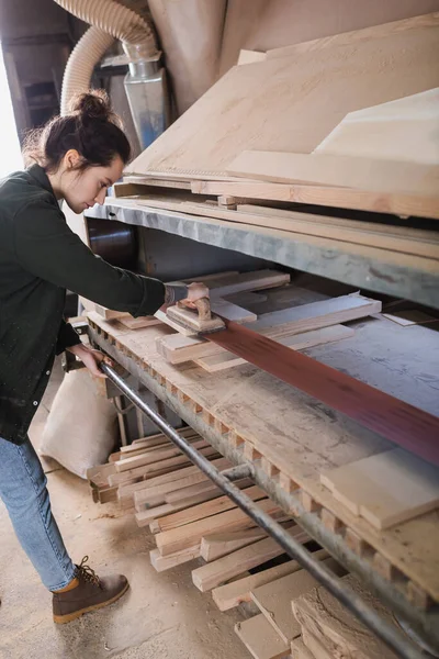 Side view of carpenter polishing planks in workshop — Stock Photo