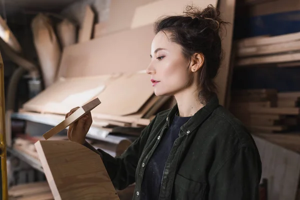 Side view of tattooed woodworker holding planks in workshop — Stock Photo