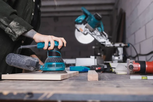 Zugeschnittene Ansicht eines Möbeldesigners mit Schleifer auf Holzbrett in der Werkstatt — Stockfoto