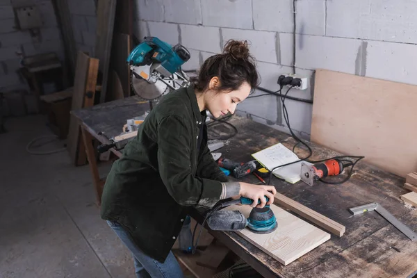 Seitenansicht des Holzarbeiterschleifbretts in der Nähe von Werkzeugen und Gehrungssäge in der Werkstatt — Stockfoto