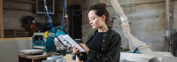 Young carpenter using digital tablet in workshop, banner — Stock Photo