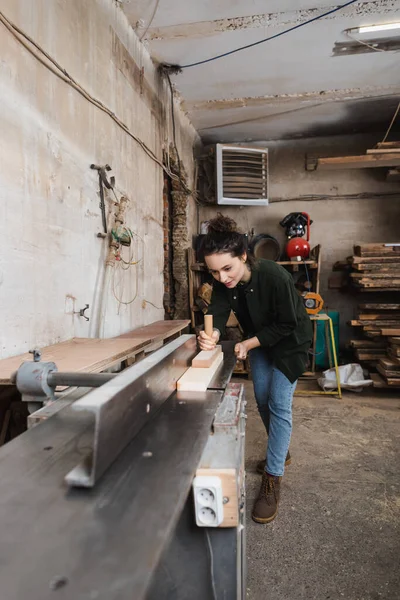 Lavoratore di legno tatuato che lavora con tavola e macchina per falegnameria — Foto stock