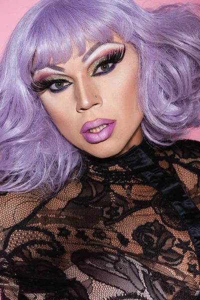 Eccentric man in purple wig and bright makeup looking at camera isolated on pink — Stock Photo