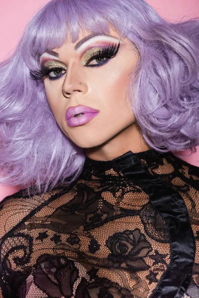 Man with spectacular makeup, in wig and lace clothing looking at camera isolated on pink — Stock Photo