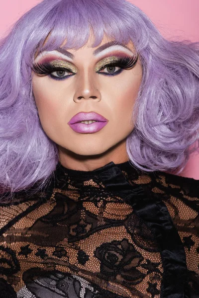Портрет человека в эффектном макияже и фиолетовый парик глядя на камеру изолированы на розовый — стоковое фото
