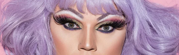 Vista parcial de drag queen en peluca púrpura mirando a la cámara, banner - foto de stock