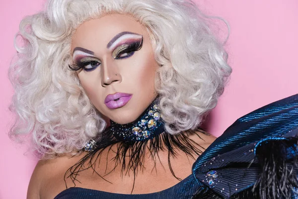 Porträt einer Transgender-Person mit blonder Perücke und glänzender Kette auf rosa — Stockfoto