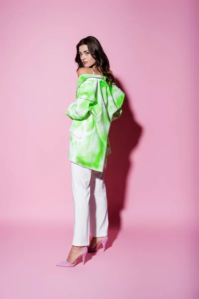 Full length of brunette woman in stylish outfit posing on pink — Stock Photo