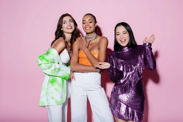 Mujeres multiétnicas felices en trajes de moda posando en rosa — Stock Photo