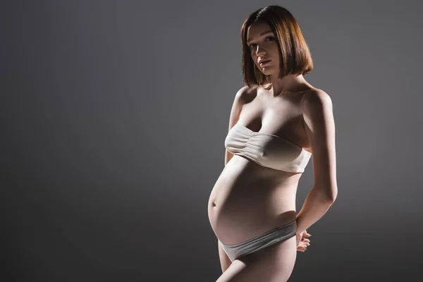 Femme enceinte en sous-vêtements posant isolé sur gris — Photo de stock