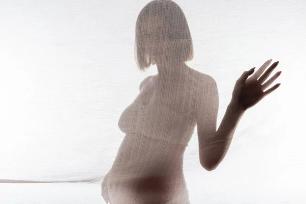 Young pregnant woman in underwear touching fabric on grey background — Stock Photo