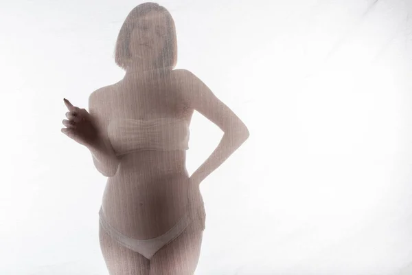 Femme enceinte en sous-vêtements toucher tissu sur fond gris — Photo de stock