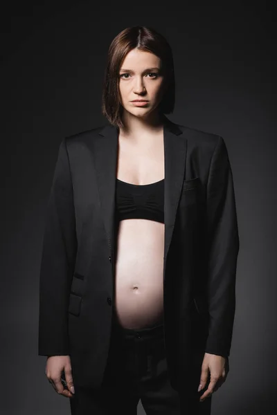Donna incinta in alto e giacca guardando la fotocamera isolata su grigio scuro — Foto stock