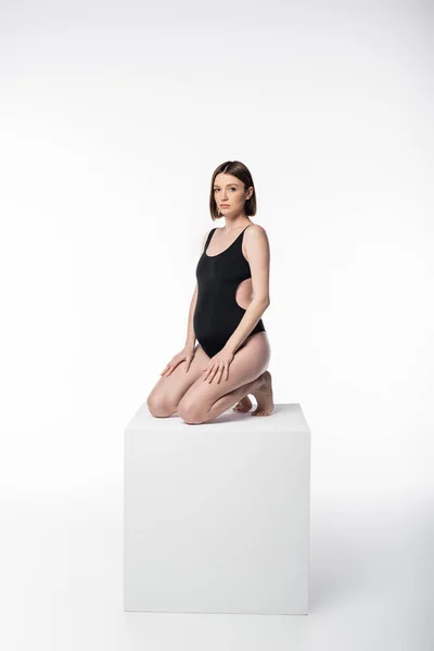Schwangere Frau im Badeanzug posiert auf Würfel auf weißem Hintergrund — Stockfoto