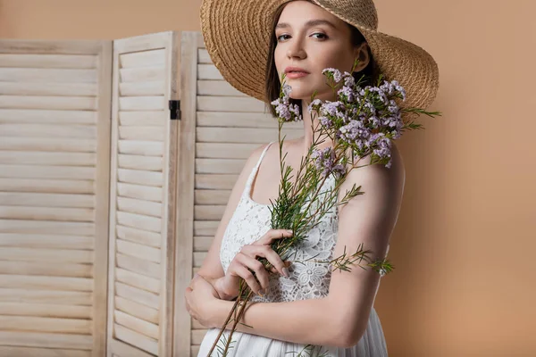 Pregnant woman in dress holding plant near folding screen isolated on beige — Stock Photo