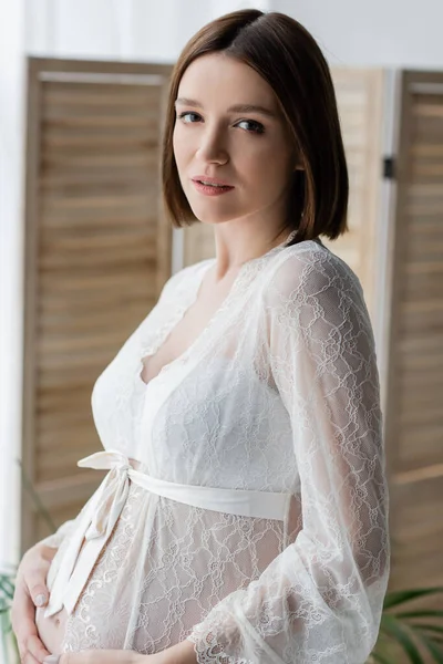 Portrait de femme enceinte en robe regardant la caméra à la maison — Photo de stock