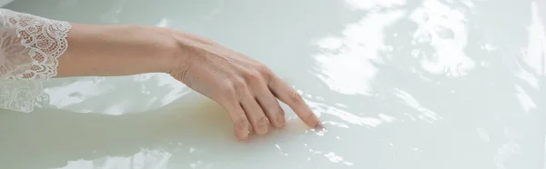 Cropped view of woman touching water in bathtub, banner — Stock Photo