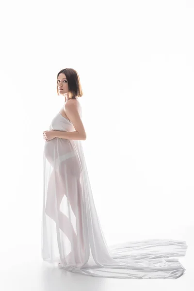 Femme enceinte en tissu et culotte regardant la caméra sur fond blanc — Photo de stock
