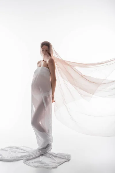 Pregnant woman in cloth closing eyes and posing on white background — Stock Photo