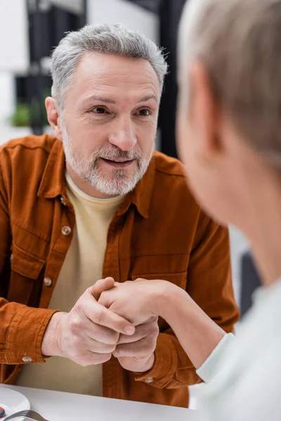 Middle aged man holding hand of blurred wife in kitchen — Stock Photo