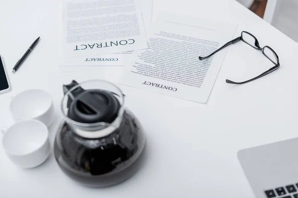 Vista dall'alto dei contratti vicino a caffè e dispositivi sul tavolo a casa — Foto stock