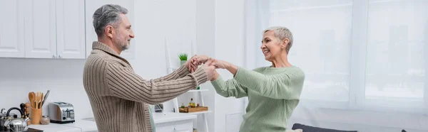 Pareja positiva cogida de la mano en la cocina, pancarta - foto de stock