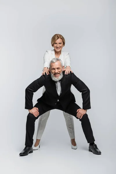 Cheerful mature bride and groom looking at camera on grey background — Stock Photo