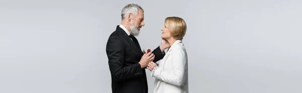 Side view of middle aged man touching girlfriend and holding jewelry box isolated on grey, banner — Stock Photo