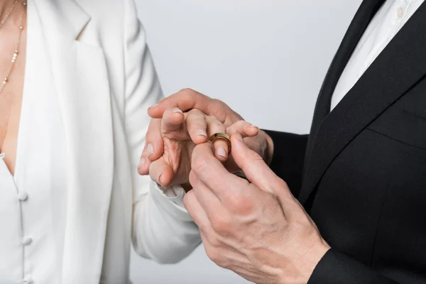 Ausgeschnittene Ansicht des Bräutigams trägt Ring am Finger der Braut in formeller Kleidung isoliert auf grau — Stockfoto
