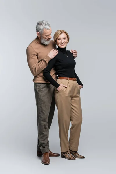 Stylish mature man hugging wife on grey background — Stock Photo