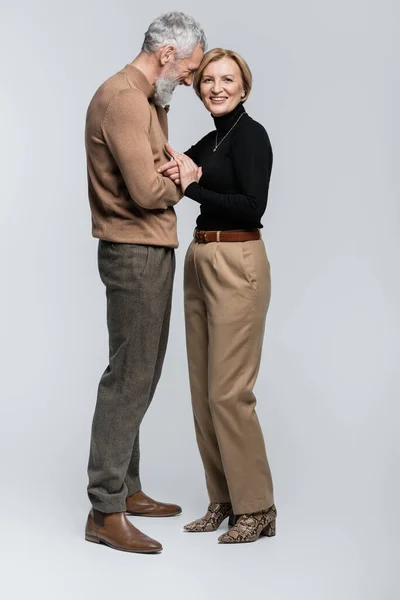 Positive ältere Mann Blick auf stilvolle Frau auf grauem Hintergrund — Stockfoto