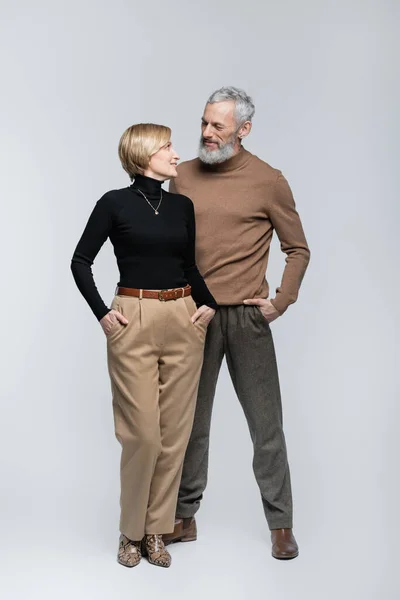 Trendy mature man looking at blonde wife on grey background — Stock Photo